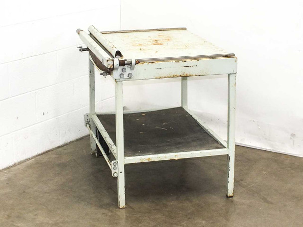 Industrial guillotine paper cutter shear — three-quarter rear view showing blade arm extended, lower shelf, and steel stand frame with paint wear