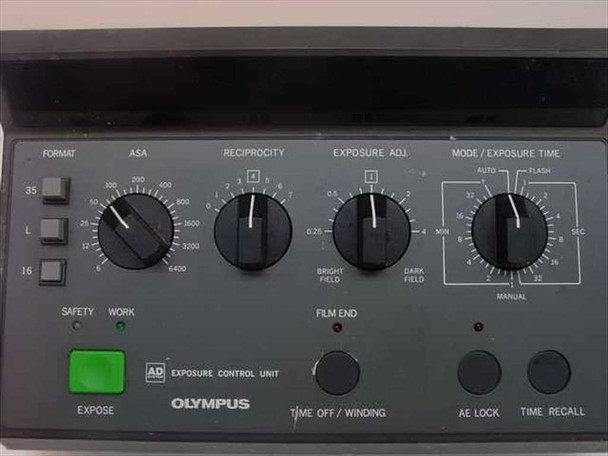 Olympus PM-CBAD front panel close-up showing Format selector (35/L/16), ASA dial, Reciprocity dial, Exposure Adj dial, Mode/Exposure Time dial, Expose button, Film End indicator, AE Lock, and Time Recall buttons