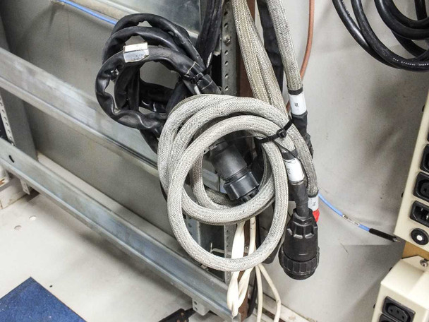 Xicom Technology rack cabinet — lower interior view showing braided cable bundles with circular multi-pin connectors coiled near base