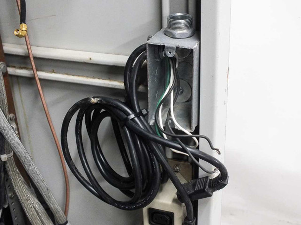 Xicom Technology rack cabinet — interior lower side showing conduit junction box with AC power wiring and black power cord coiled below