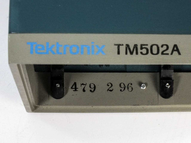 Tektronix TM502A model identification label close-up showing blue Tektronix logo, model number TM502A, and date/serial stamp on front lower bezel