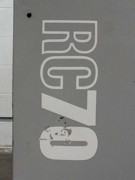 RC70 large white logo decal on gray cabinet side panel showing minor paint peeling at base of lettering