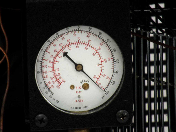 Internal refrigeration section of Thermonics T-2423 with compressor, refrigerant pressure gauge, condenser coil with fan guard, and copper refrigerant lines visible