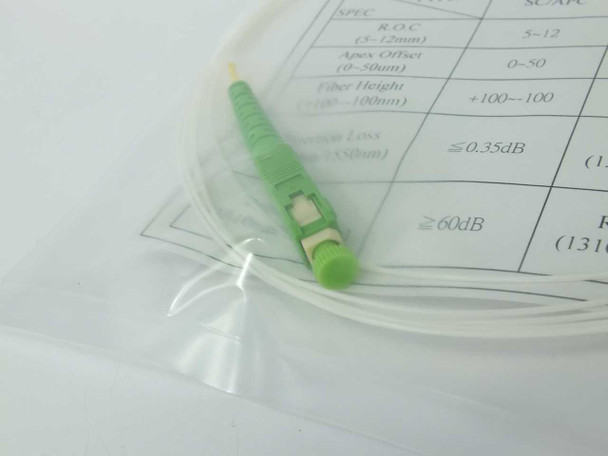 Close-up of SC/APC green connector end on 900um singlemode fiber jumper with coiled white cable visible