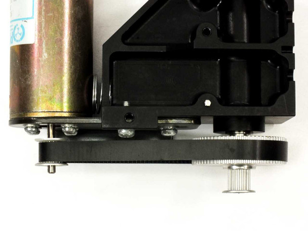 Underside view of Pittman motor and black aluminum gear frame showing dual gear shafts, belt, and motor body with surface patina