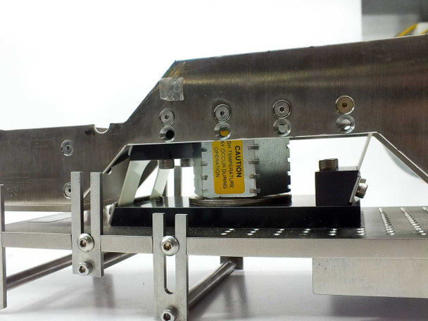US Vibra 2028-A internal drive assembly – alternate angle under-track view showing electromagnetic driver, caution label, mounting hardware, and perforated deck underside