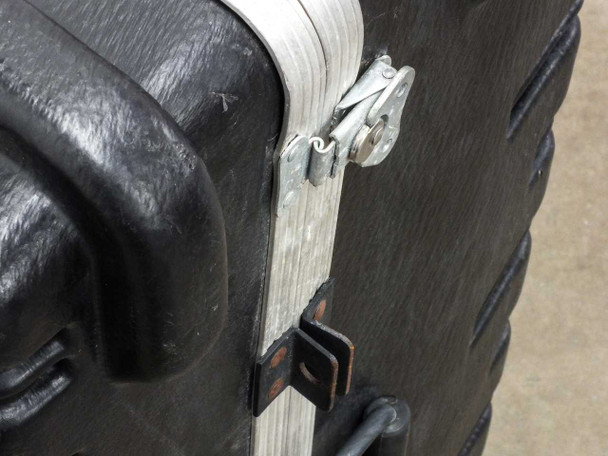 Close-up of exterior metal latch and clasp hardware on hard travel case showing wear and aluminum trim edge