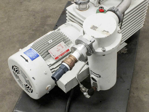 Close-up of GE motor and pump coupling area showing oil drain/fill port with blue cap, hot surface warning label, and vacuum port with dust cap removed