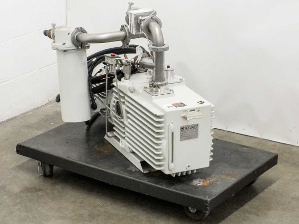 Leybold D60AC TRIVAC vacuum pump on wheeled dolly, front-right view showing TRIVAC badge on pump body and oil filter/mist separator canister on left with stainless piping and NW clamp fittings
