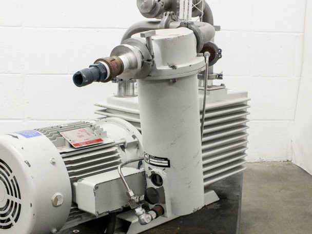 Close-up of oil filter/mist separator canister and vacuum inlet piping with NW clamp fittings and stainless elbow, motor in background