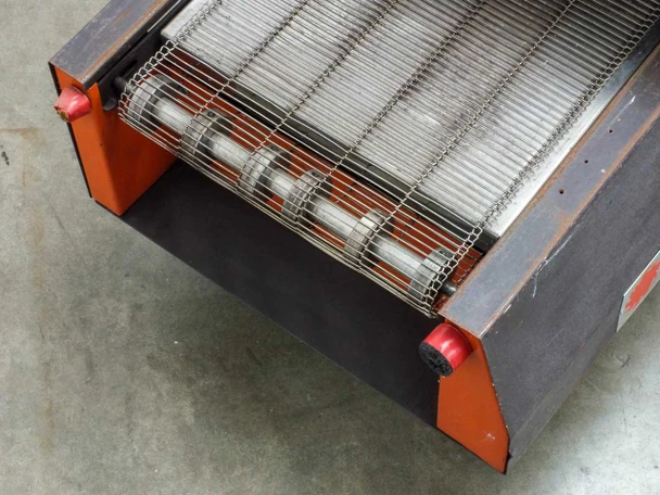 Glo-Quartz TR91-12A – underside/rear view of belt drive roller showing stainless mesh belt and quartz lamp array