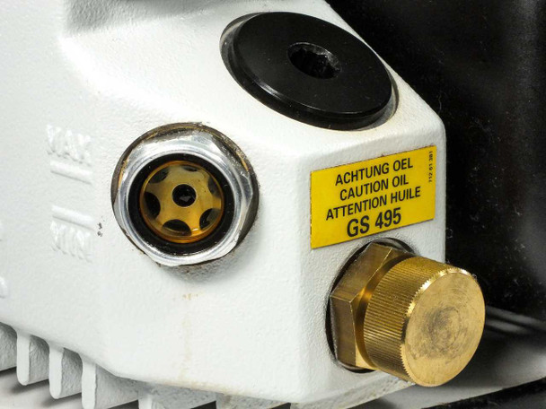Close-up of oil filler/drain area showing brass sight glass, oil fill port, GS 495 caution label, and brass drain plug