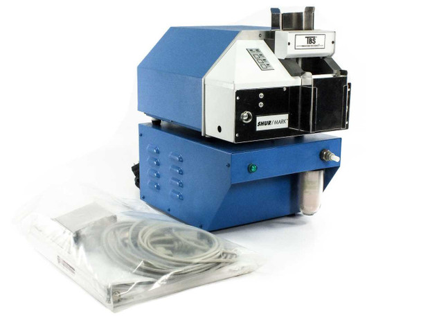 Triangle Biomedical Sciences TBS SHUR/MARK E22-01MWSDE slide labeler – front-left 3/4 view showing blue housing, TBS badge, and accessory cables laid in front