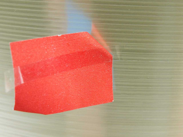 Close-up of transparent PET tape roll surface with red protective tab visible on tape end