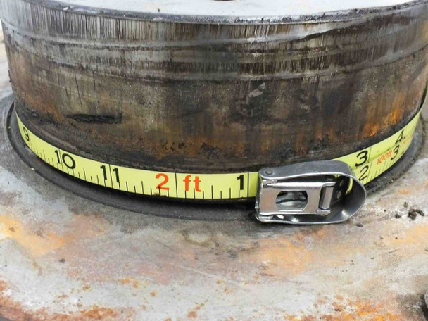 Close-up of the outer edge of the rotary output table hub showing surface rust and corrosion, with tape measure indicating approximately 24-inch circumference