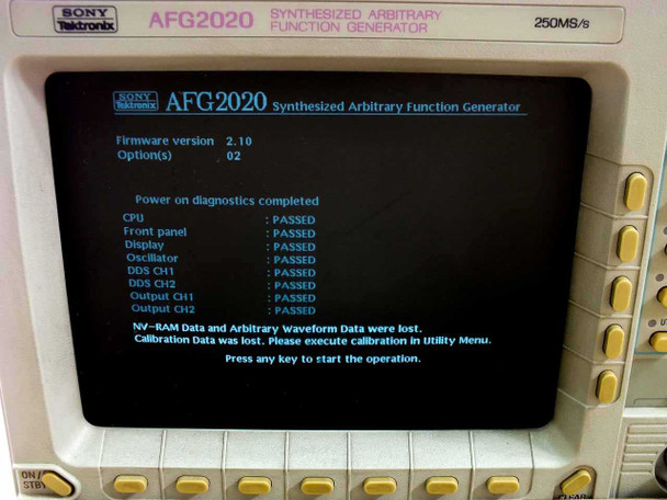 Sony Tektronix AFG2020 display close-up showing power-on diagnostics: all subsystems PASSED (CPU, Front Panel, Display, Oscillator, DDS CH1/CH2, Output CH1/CH2); Firmware 2.10, Option 02; NV-RAM and calibration data lost message visible