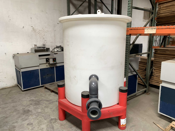 Snyder Industries 440 gallon white polyethylene water tank on red ASM support stand with bottom PVC outlet fitting, warehouse setting