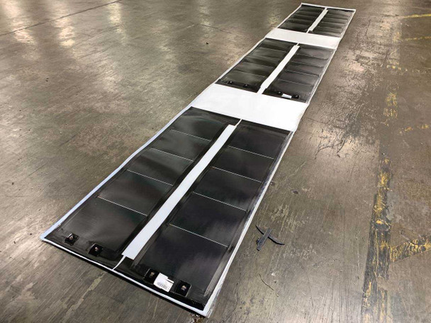 Xunlight XRS5-42 42W flexible amorphous solar panels — angled full-length view of six-panel sheet on warehouse floor showing thin-film cell layout and white edge framing