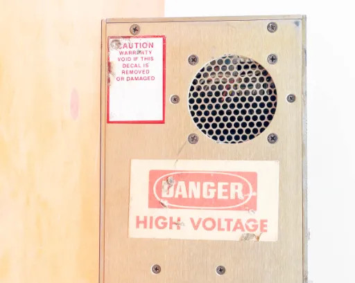 Comdel CPS-200AX RF power supply side panel showing DANGER HIGH VOLTAGE decal, cooling vent, and CAUTION warranty void sticker