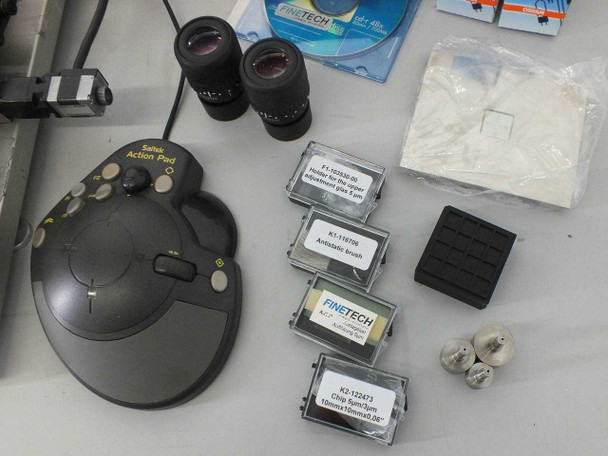 Accessories laid out including Saitek Action Pad joystick, two Leica eyepieces, Finetech accessory boxes (part numbers F1-502650-01, K1-116728, K2-132473 visible), foam pad, and small hardware pieces