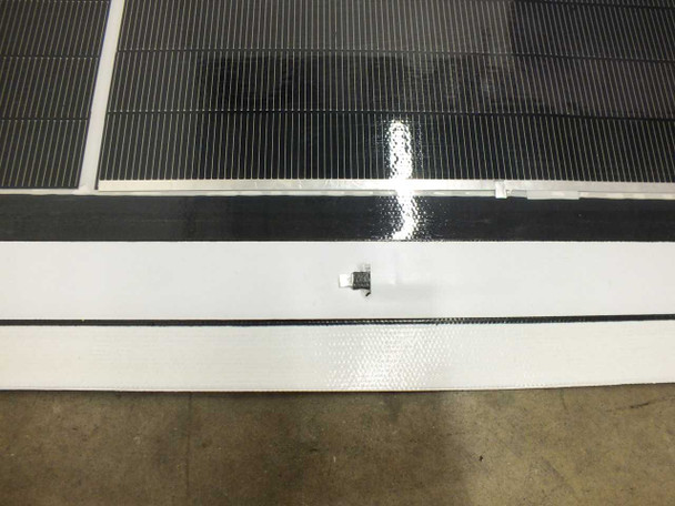 Close-up of SoloPower SP3L-160 solder point tab connection area at panel edge — small metal solder tab visible on white backing strip