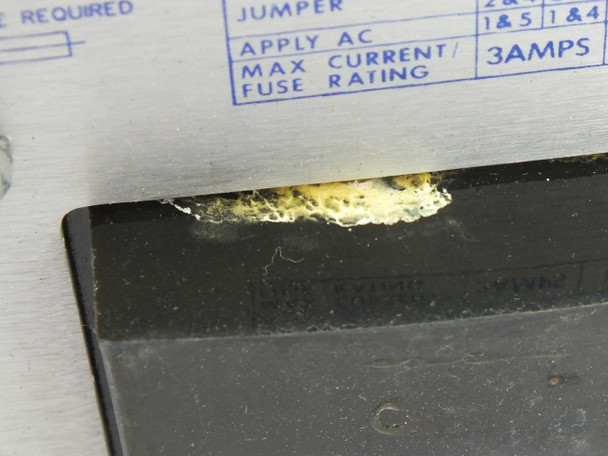 Close-up of Power-One HE15-9-A terminal block showing degraded adhesive residue buildup alongside jumper configuration label indicating 3A max fuse rating