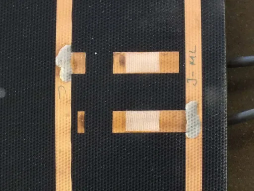 Close-up of Uni-Solar PVL-136 bus bar junction area showing copper interconnects, bypass diode pads and hand notation