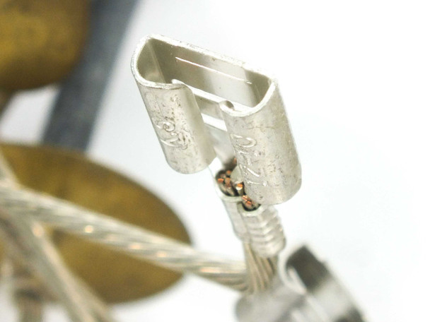 Macro close-up of removable 3/8-inch spade/terminal clip on MC3 solar cable end — brass construction detail