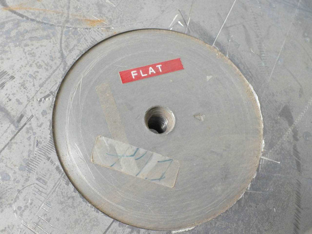 Close-up of center hub of a Lapmaster flat lapping plate with red label reading 'FLAT' and threaded center hole