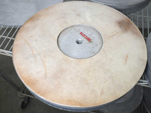 Top view of a Lapmaster flat lapping plate with tan/beige abrasive surface, red 'FLAT' label at center hub, surface discoloration