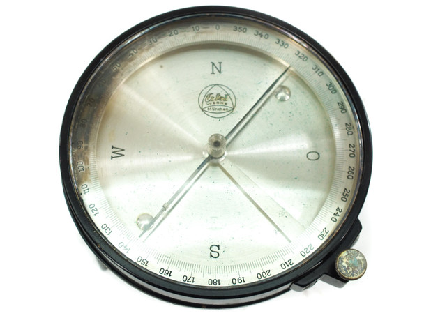 Close-up of detached surveying compass face showing N/S/E/W cardinal points, degree scale 0–360, and needle