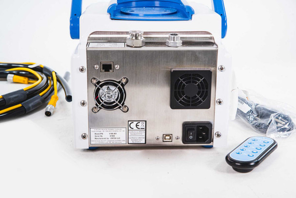 EMTEK V100 rear panel close-up showing rating label, CE mark, dual cooling fans, IEC power inlet, USB and RJ45 ports, and wireless remote