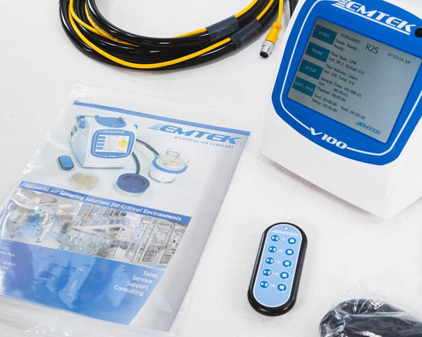 EMTEK V100 front panel close-up with RS2 label on LCD screen, EMTEK product brochure and remote control visible