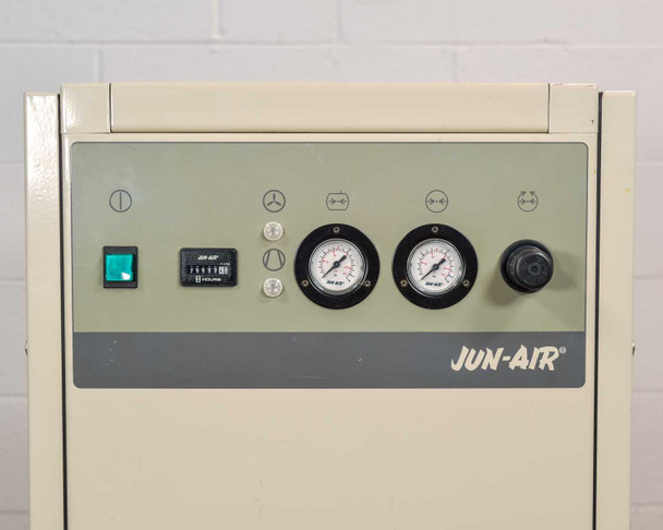 Jun-Air 2000-25M front control panel close-up showing green power switch, hour meter, dual pressure gauges, and rotary selector knob