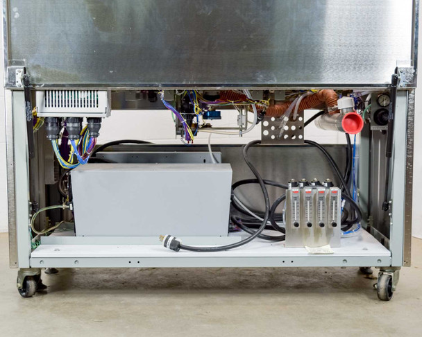 Interior rear lower bay view showing gray transformer/power supply enclosure, multi-color wiring bundles, Dwyer rotameter flow meter bank (4 meters), and solenoid valve manifold