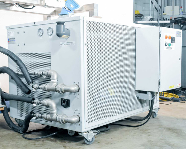 Rear of Opti Temp chiller unit showing stainless steel MNPT process pipe connections, insulated hoses, pressure gauges, and perforated steel cabinet