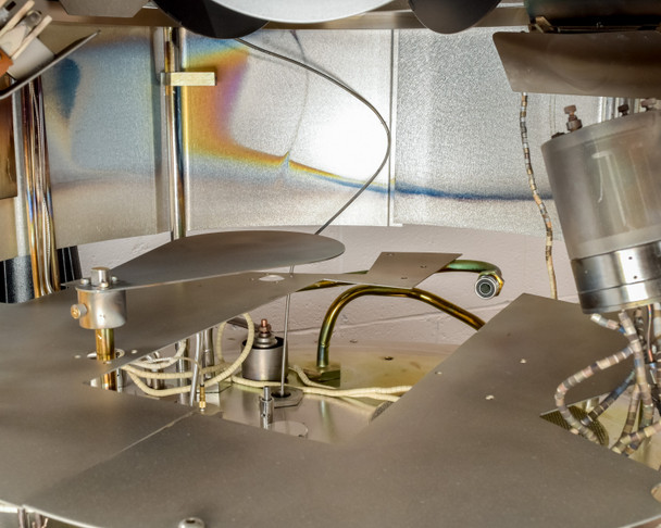 CHA Industries SEC-600 internal deposition assembly — shutter plate, substrate stage, ion source arm, and thin-film iridescent residue on interior walls