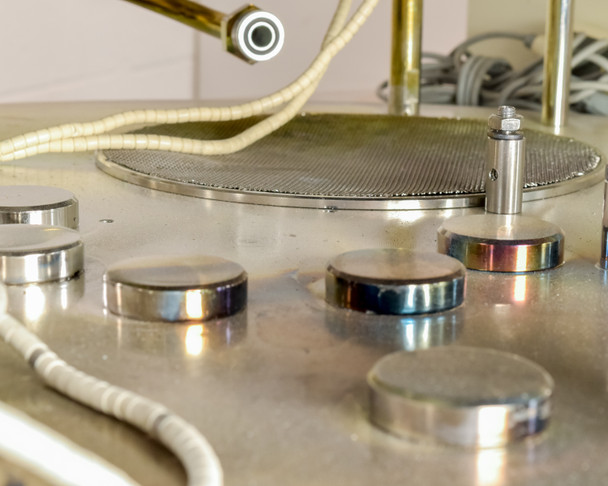 CHA Industries SEC-600 evaporation source hearth area — multiple circular target pucks and perforated substrate platen on stainless steel table