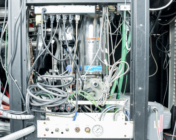 CHA Industries SEC-600 internal cabinet view — dense wiring harness, plumbing lines, pressure gauge, valves, and subsystem modules behind rear access panel