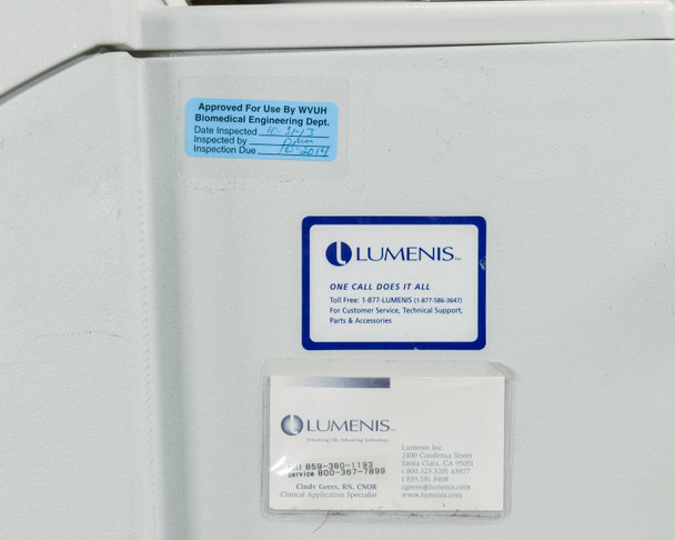 Close-up of Lumenis unit side panel showing WVUH Biomedical Engineering Department inspection approval sticker, Lumenis service contact label, and Lumenis clinical representative business card
