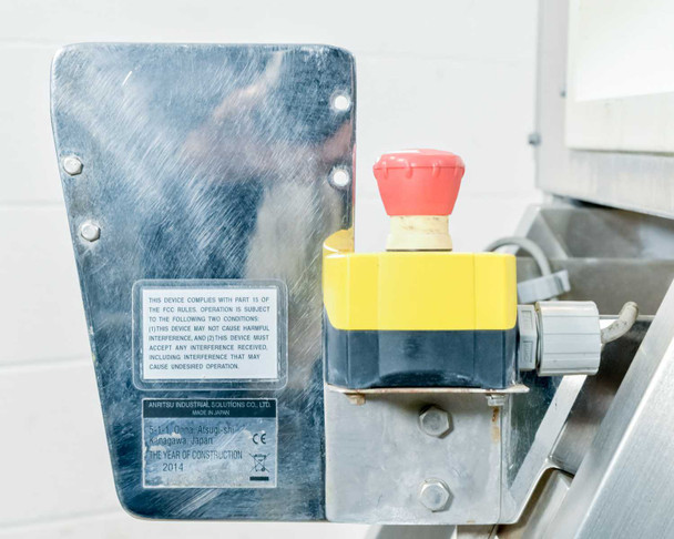 Anritsu KD8125AW emergency stop button assembly — red mushroom E-stop on yellow base mounted to side bracket