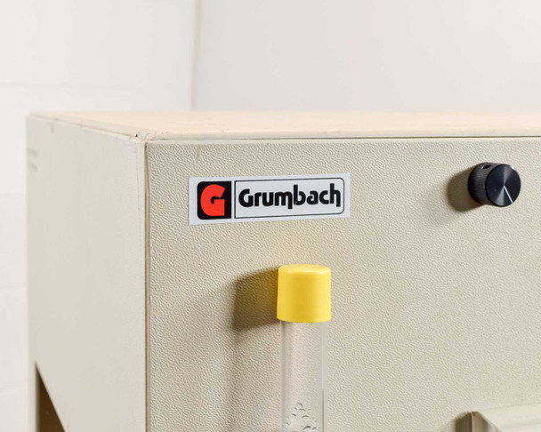Grumbach Brutgeräte logo badge on top-left of incubator cabinet with yellow water reservoir tube visible below