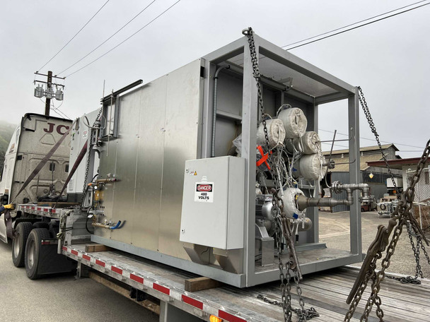 Nabertherm NR 1000/11 vacuum furnace loaded on flatbed truck, side view showing stainless steel exterior panels and vacuum pump connections