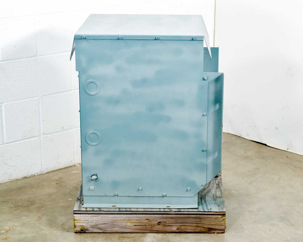 HPS NMF025LE transformer – left side panel view showing bolt pattern, two circular knockouts, and mounting flange; unit resting on wooden pallet