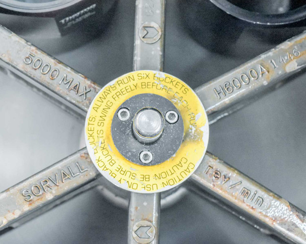 H6000A rotor hub center showing yellow caution label — 'Always Run Six Buckets', 5000 MAX speed marking, and Sorvall rev/min rating