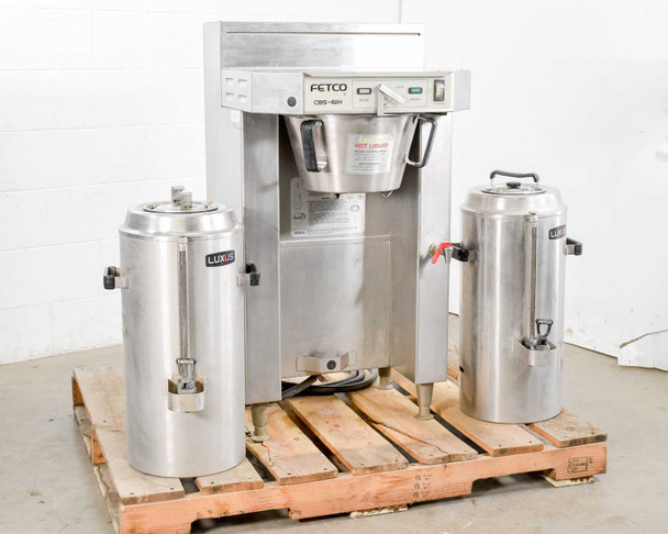 Fetco CBS-61H commercial coffee brewer with two Luxus TPD-30 stainless steel thermal dispensers on pallet — full front three-quarter view