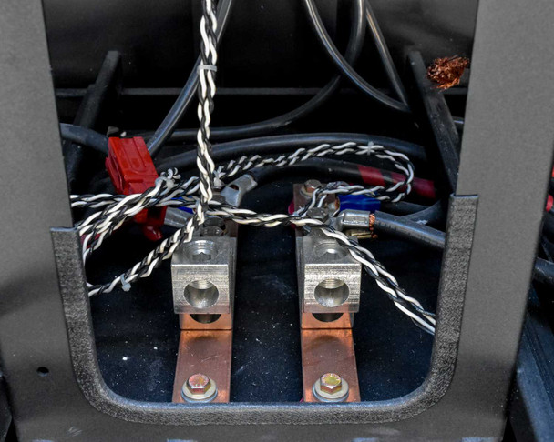 Battery cabinet lower wiring compartment showing DC bus copper lugs and interconnect cables