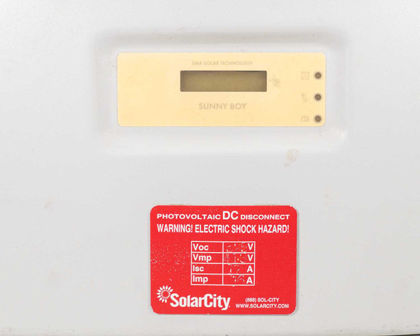 SMA Sunny Boy SB 3800-US-10 — close-up of front panel LCD display reading 'Sunny Boy' and SolarCity photovoltaic DC disconnect warning label with Voc/Vmp/Isc/Imp fields