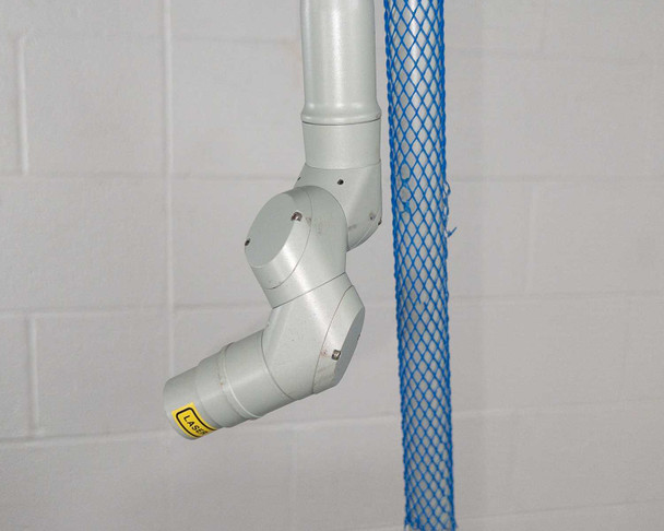 Lumenis AcuPulse 40 articulated multi-joint laser delivery arm end section with laser hazard label, photographed separately
