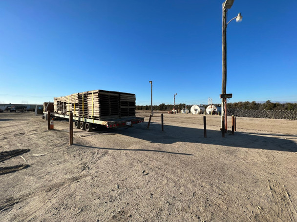 Flatbed truck loaded with stacks of 48x48 heavy duty treated wood pallets ready for transport